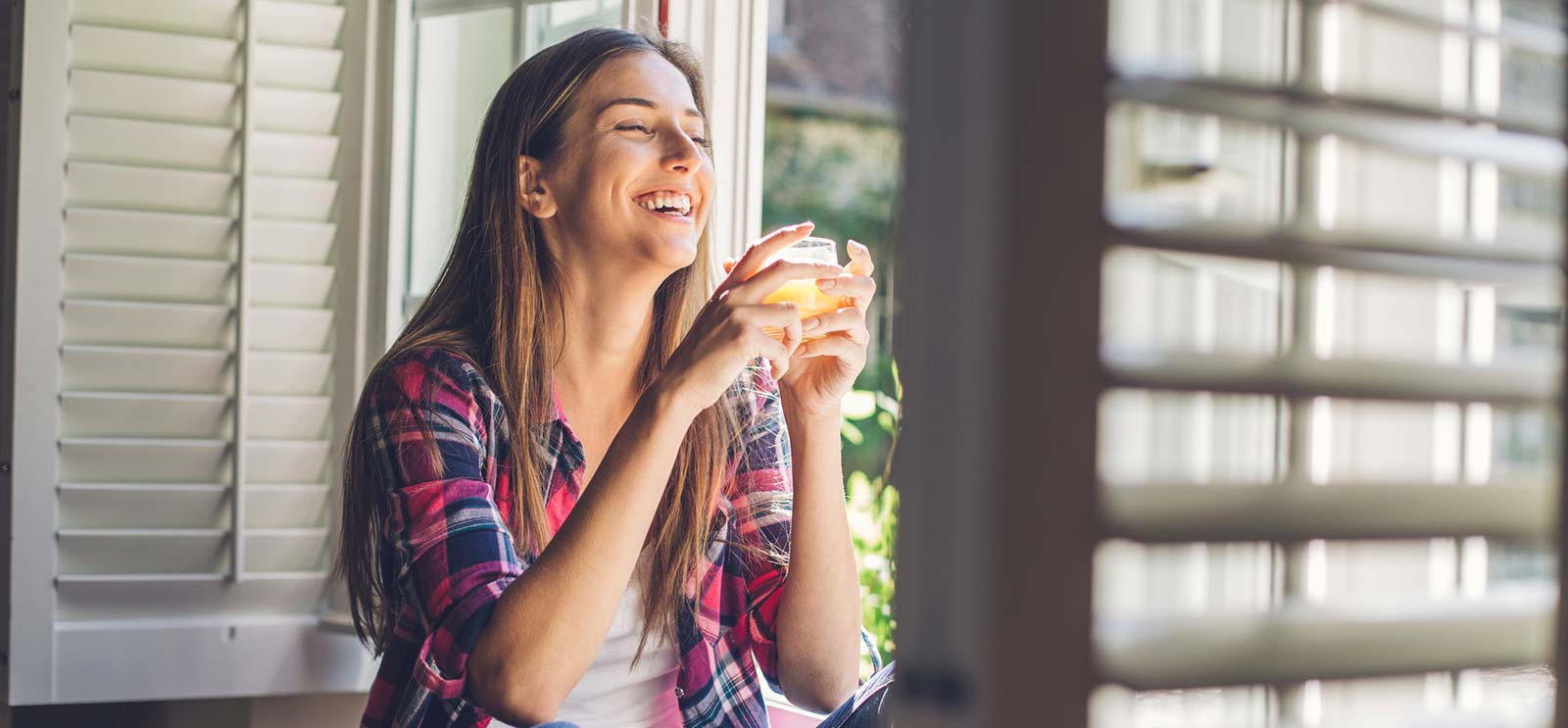 Young woman drinking orange juice in living room