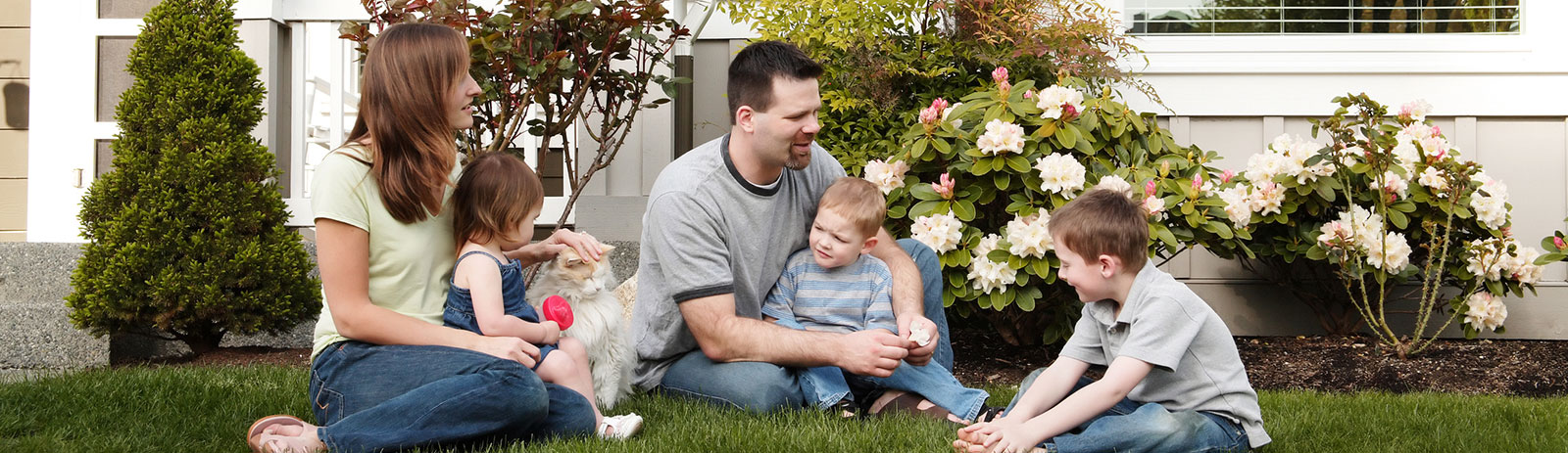 Young family sitting on front lawn
