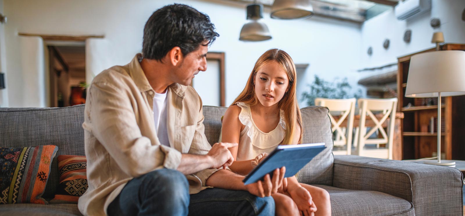 Father and daughter using tablet in living room